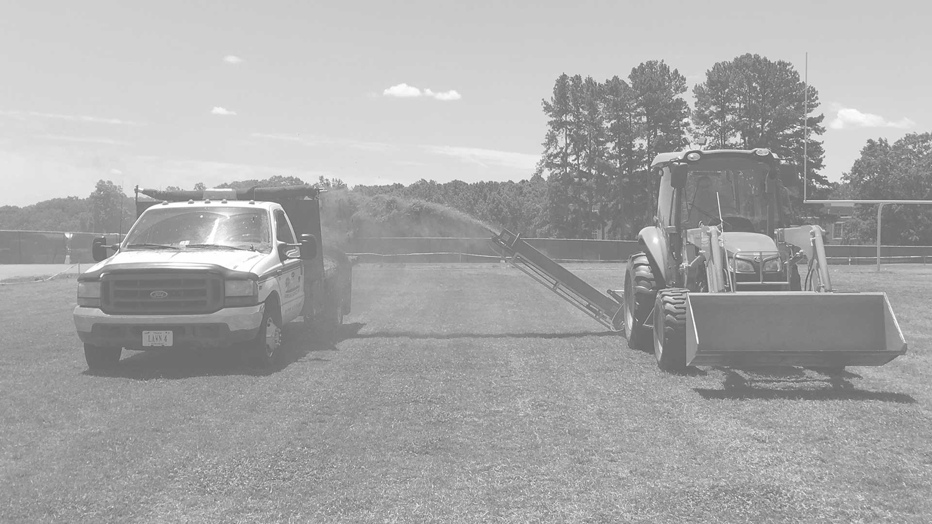 Tractor and truck on sports field.